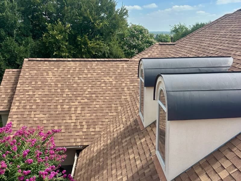 Completed shingle roof with barrel-topped dormers and clean valley work.
